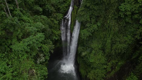 looking down at the powerful aling-aling waterfall in bali, indonesia on an overcast afternoon, aerial