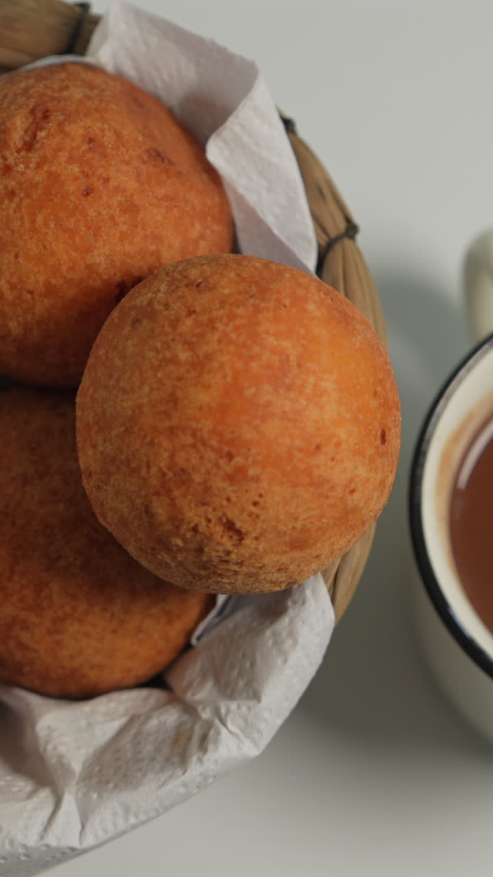Delightful close-up shot of golden, crispy buñuelos nestled in a basket. Warm lighting accentuates texture, perfect for social media in a vertical video format