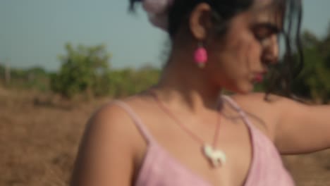 young woman in pink dress with flower in hair, outdoors, sunny day, serene atmosphere