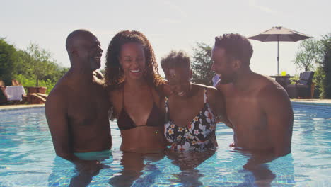 Multi-Generation-Family-With-Adult-Offspring-On-Summer-Holiday-Relaxing-In-Swimming-Pool-Together