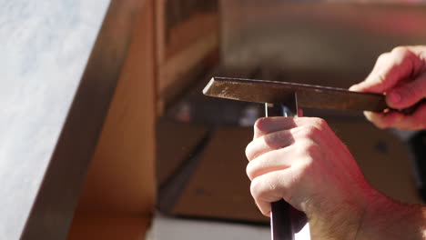 close up shot of the hands of a construction worker using a large rough metal file to grind and smooth a piece of sheet metal angle iron on the jobsite