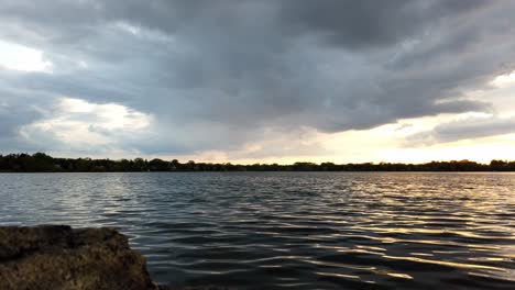 Lapso-De-Tiempo-Durante-La-Hora-Dorada-En-Un-Día-Nublado-Visto-Desde-La-Línea-De-La-Costa-Del-Lago