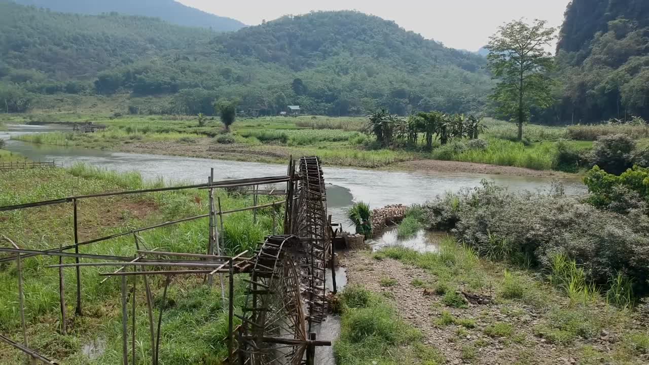 vista aérea de un hombre llevando cosechas junto a ruedas de agua de bambú en pu luong, vietnam