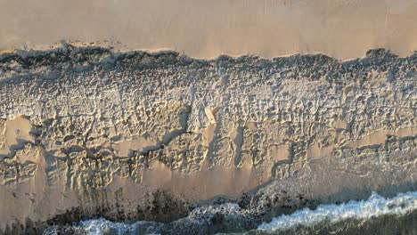 aerial - waves crashing against rocky beach in exmouth, australia, top down