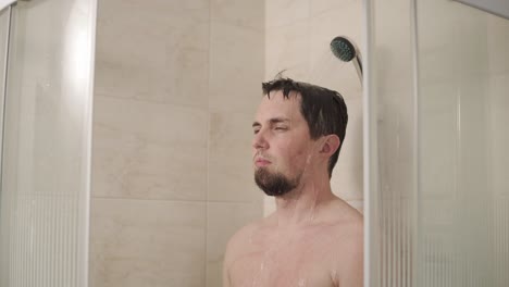 hombre bañándose en un recinto de ducha de vidrio
