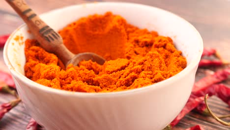 chili powder in a bowl with wooden spoon and dried chili peppers