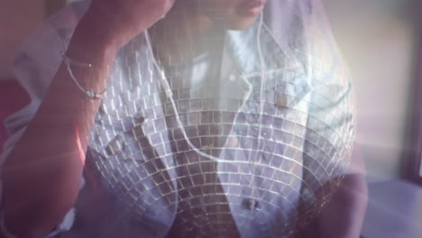 disco mirror ball spinning against woman wearing earphones