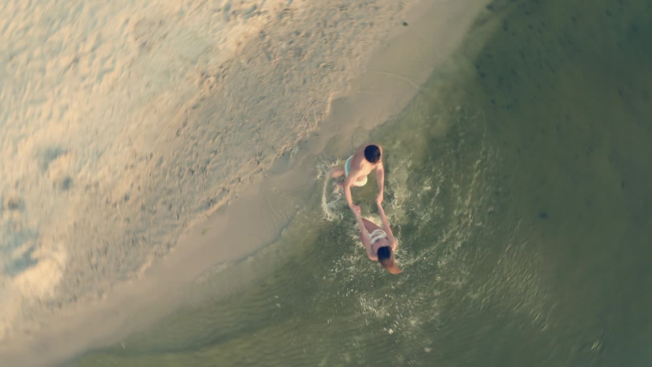 젊은 부부는 손을 잡고 물 위에서 원을 돌고 있습니다.