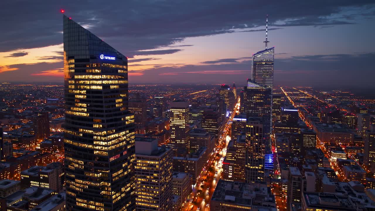 Aerial video view of a city skyline at dusk, showcasing illuminated skyscrapers and streets