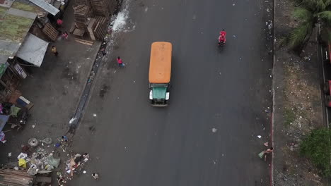 aerial shot of a jeepney travelling on a busy, dirty road of manila philippines