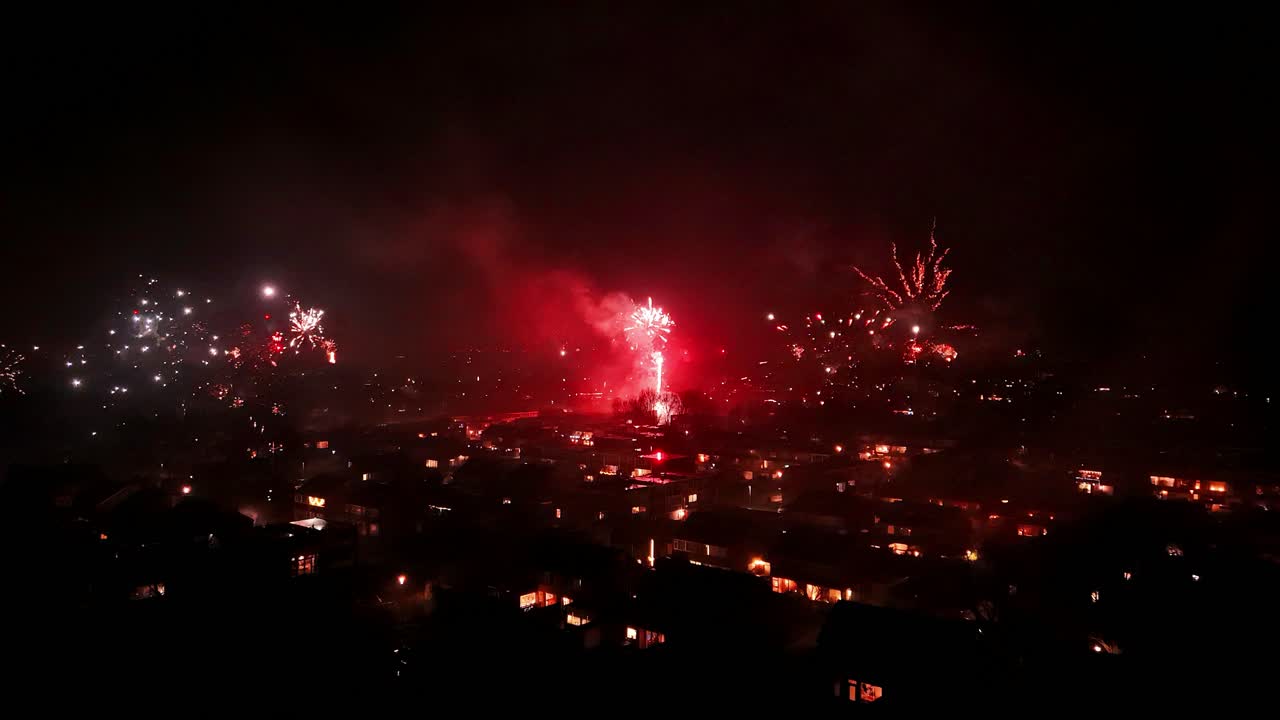 Wide view of New Year’s Eve fireworks lighting up a residential neighborhood in the Netherlands at night. Festive atmosphere, urban skyline, celebration moment, winter holiday scene