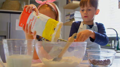 Front-view-of-cute-Caucasian-siblings-baking-cookies-in-kitchen-of-comfortable-home-4k