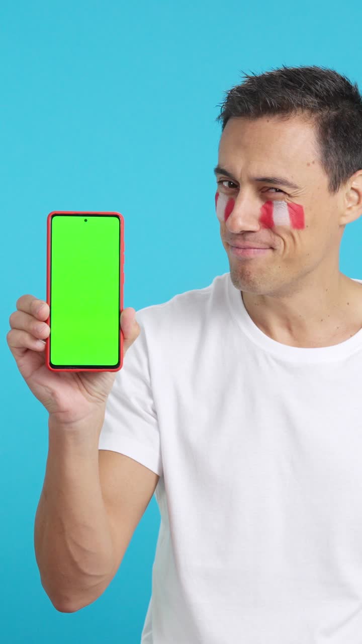 Peruvian supporter looking at his mobile smiling and showing it