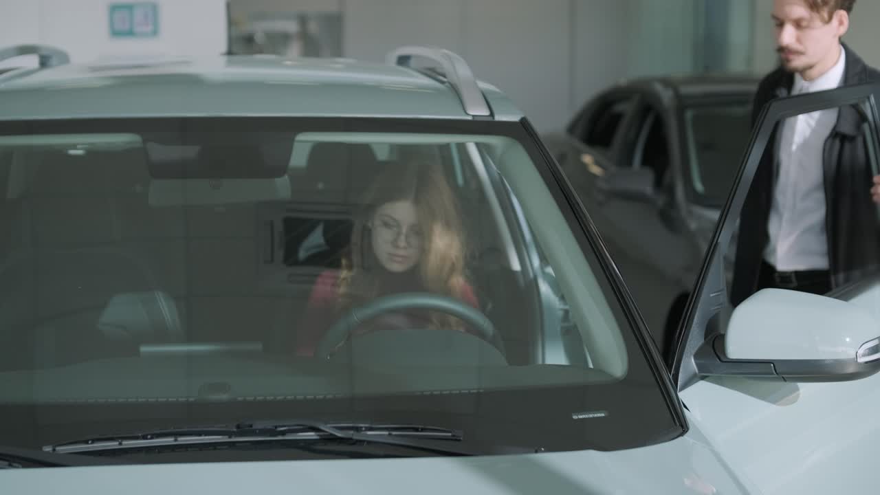 Una donna guarda un'auto nuova in una concessionaria con un venditore