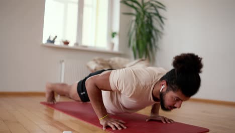 Sportive-man-training-push-ups-at-home-as-home-workout-in-apartment-with-bare-feet