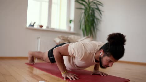 sportive man training push-ups at home as home workout in apartment with bare feet