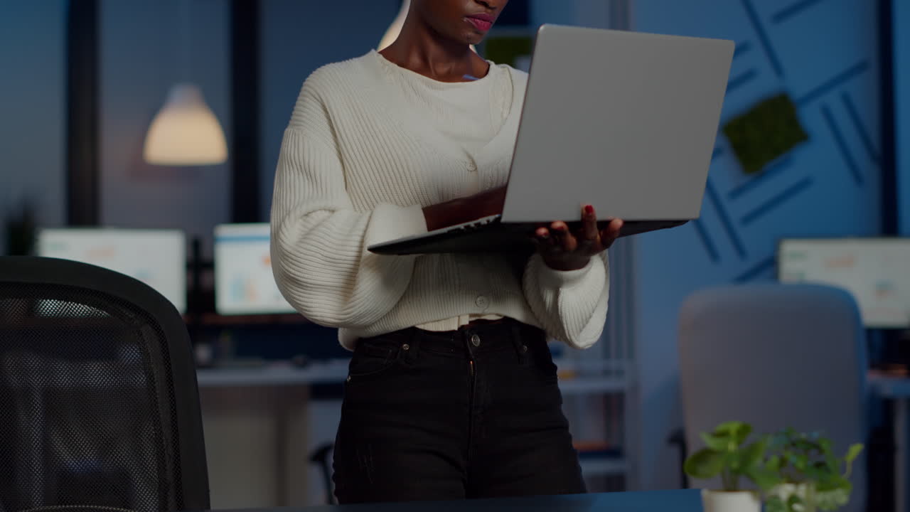 mulher de negócios exausta segurando laptop, digitando e suspirando olhando para a câmera
