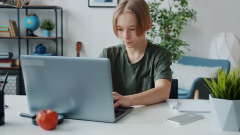 teenage student using a laptop at home