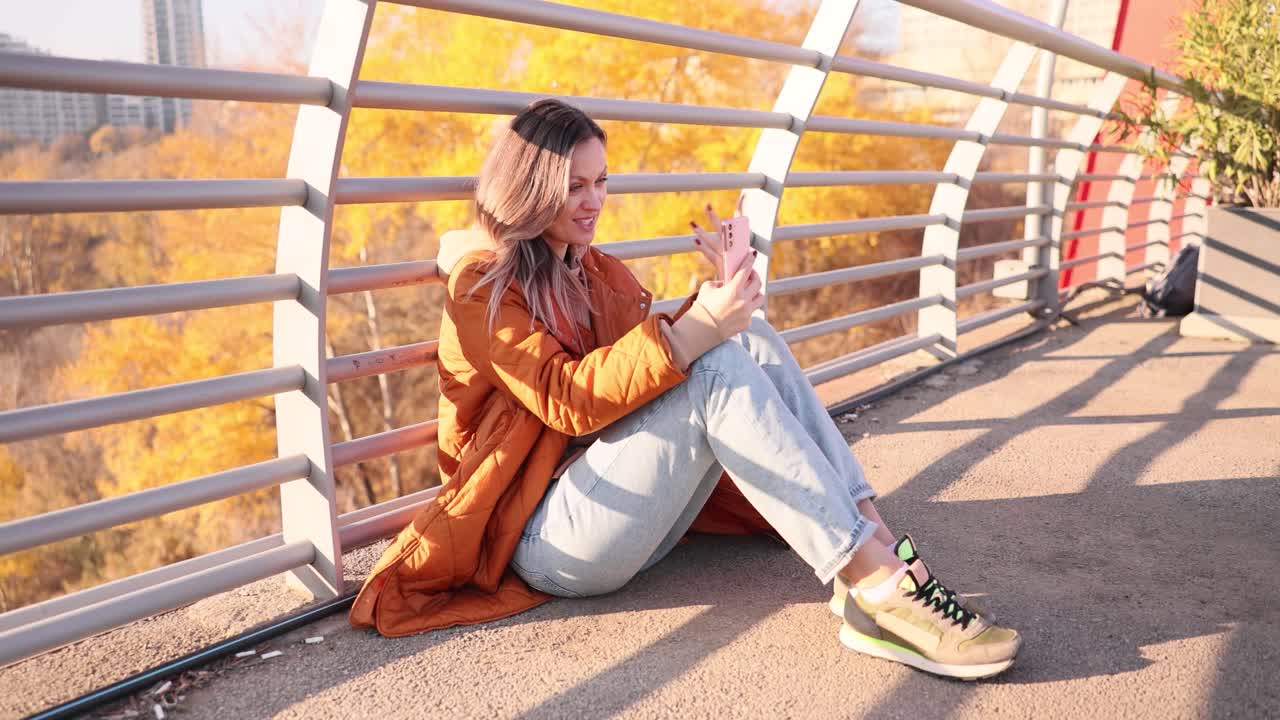 Woman using mobile phone on a bridge in autumn