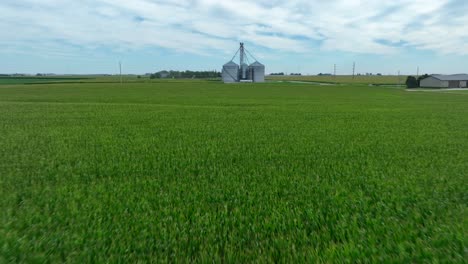 aerial flight above corn field towards grain elevator in midwest usa
