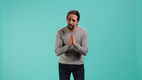 hombre juntando las manos en un gesto de mendicidad, pidiendo un favor