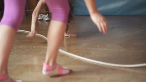 low angle slow motion shot of a group of playful girls jumping over a moving rope in a house