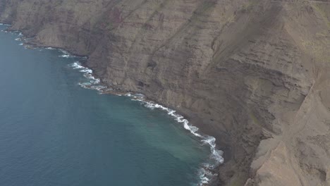 Panorama-drone-shot-of-waves-bounce-on-rocks-at-the-coast