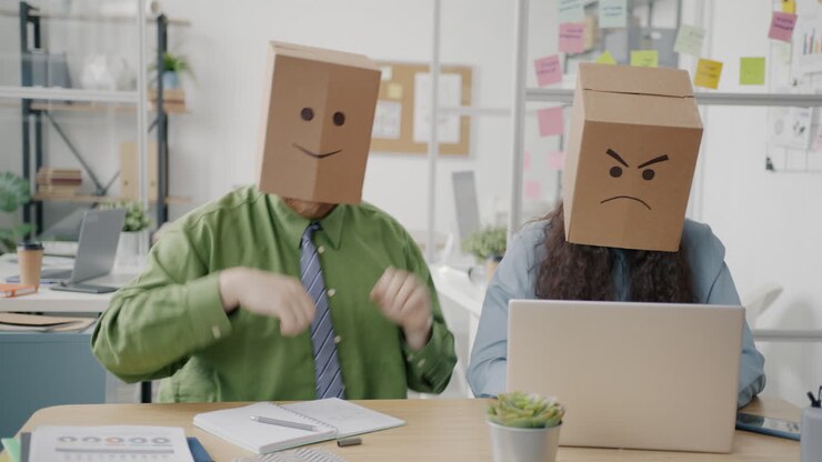 Colleghi divertenti con teste di cartone in ufficio