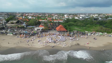 una playa ocupada llena de personas balinesas durante la ceremonia de melasti, aérea