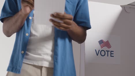 close up of man next to booth with ballot paper in american election deciding how to cast his vote 1