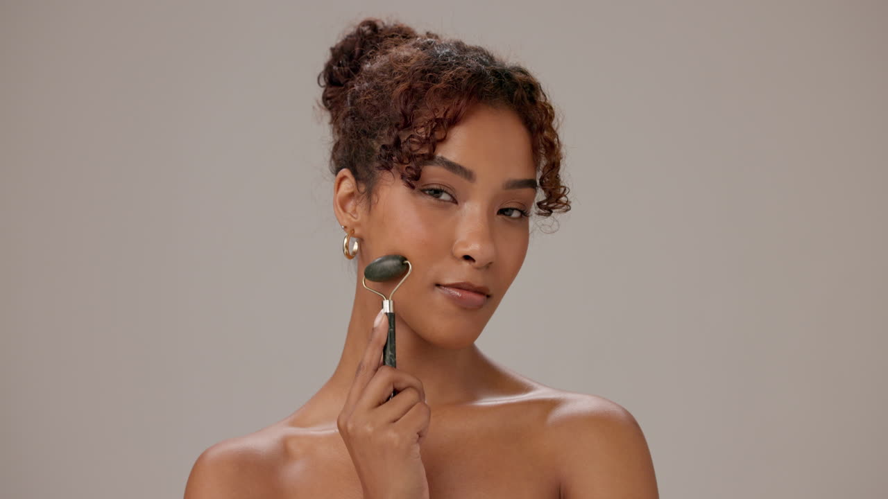 Woman smiling and holding a jade roller for skin care