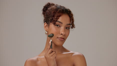 woman smiling and holding a jade roller for skin care