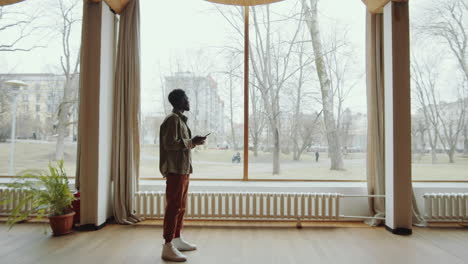 African-American-Man-Using-Smartphone-in-Library-Auditorium