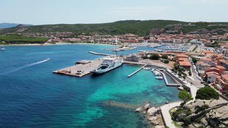 Muelles-De-Ferry-En-La-Ciudad-Portuaria-De-Palau-En-Cerdeña,-Italia---Pedestal-Aéreo-4k-Arriba