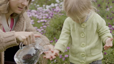 mother pouring water from jug on daughters hands outdoor