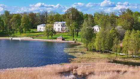 astravas manor is a centuries-old manor house surrounded by lush parkland on the shores of širvėna lake in biržai, lithuania - drone flying forward