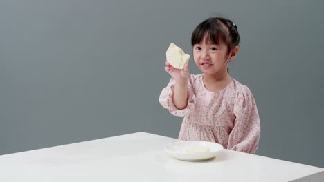 Fröhliches-Asiatisches-Mädchen-Lächelt-Und-Genießt-Es,-Zu-Hause-Knusprigen-Buttertoast-Zu-Essen