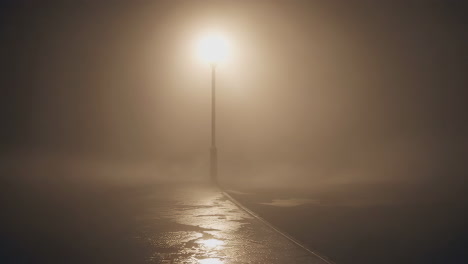 solitary street lamp in heavy fog at night
