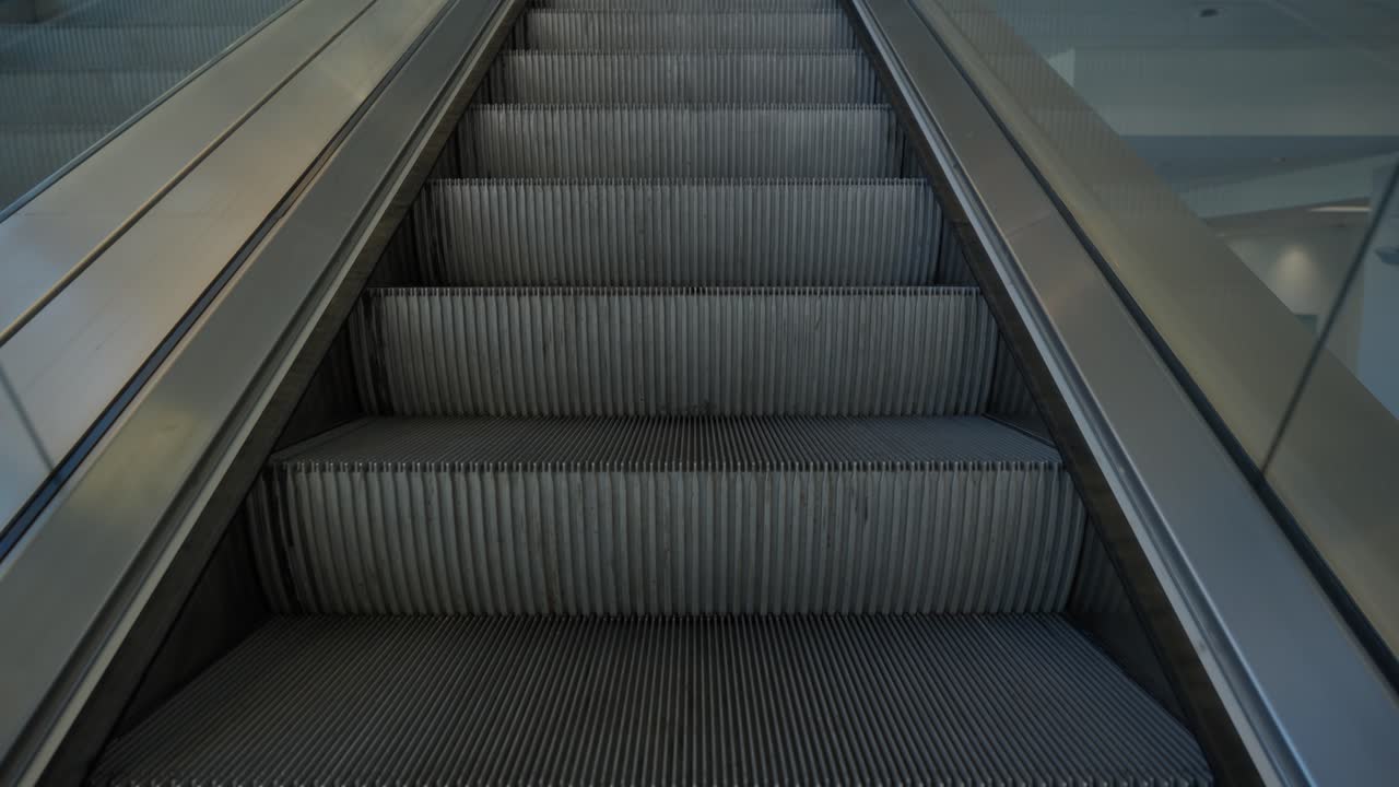 Narrow field of view close up on steps of escalator as it rides up at a large commercial center