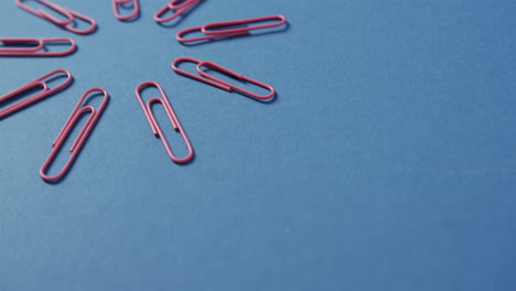 red paper clips are scattered on a blue background