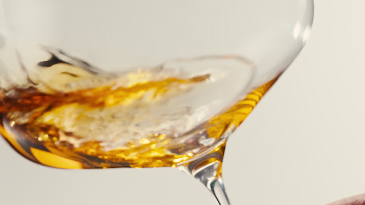 Orange or white wine bottle and glass against a sunset in a peaceful vineyard, pouring of ecological natural wine.