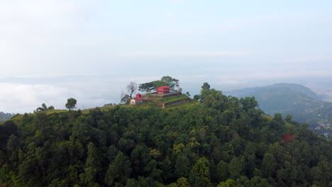 drone push in and tilt down to temple on top of lush green tropical mountain overlooking valley below