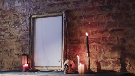 video de una pila de libros, marco con tela de araña, cráneo y velas en el fondo de la pared de ladrillo