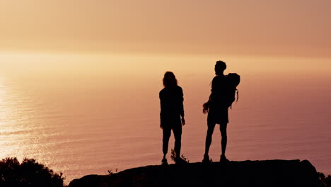 couple silhouetted against sunset over ocean