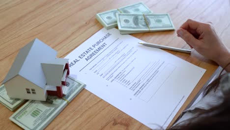 woman buying a house reading the real estate purchase agreement before signing. - close up shot
