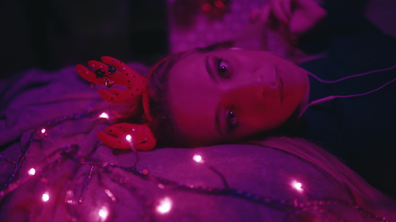 Frau mit Weihnachtshörnern hört Musik im Schlafzimmer