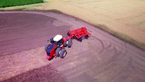 agricultural tractor with trailer for ploughing working on cultivated field