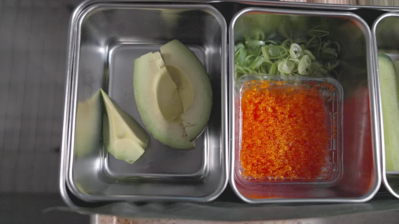 A static sliding shot showcasing the essential ingredients needed to make sushi, including fresh fish, rice, seaweed, and more, highlighting the preparation process.