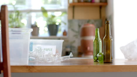 cajas de plástico de segregación para residuos, botellas de plástico y vidrio en la mesa en la cocina, cámara lenta
