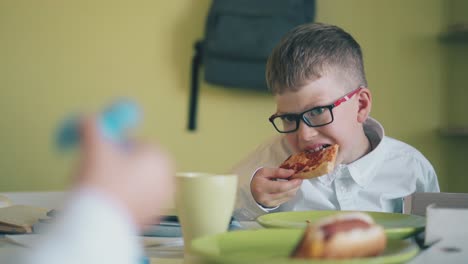pupil-has-dinner-with-pizza-by-friend-with-spinner-at-table